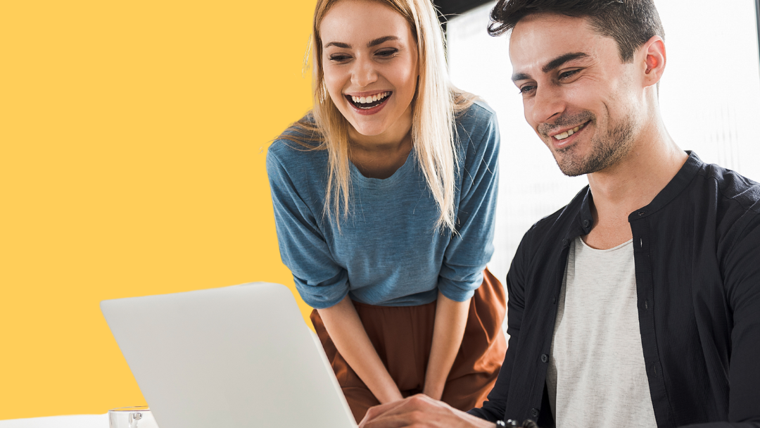 A man and a woman are looking at a laptop computer.
