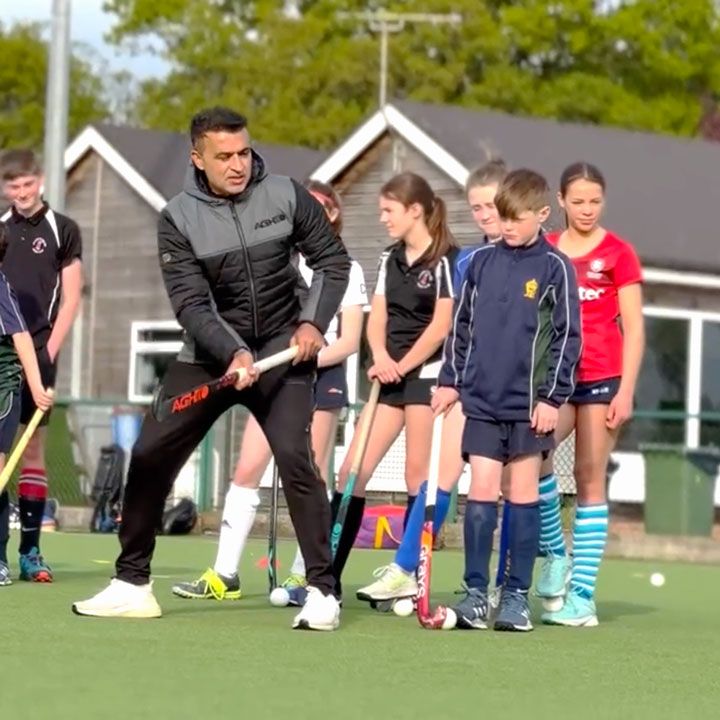 A man is holding a hockey stick in front of a group of children