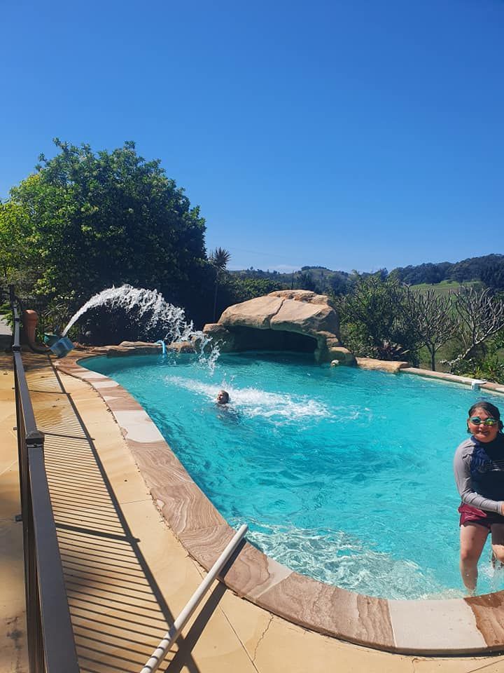 A Woman Is Standing In A Swimming Pool With A Fountain In The Background — Gary Arnold Water Supplies in Uki, NSW