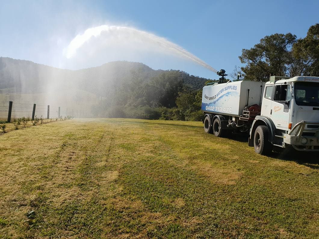 A Truck Is Spraying Water On A Grassy Field — Gary Arnold Water Supplies in Uki, NSW