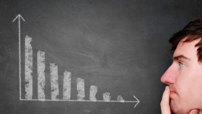 A man is looking at a graph on a blackboard.
