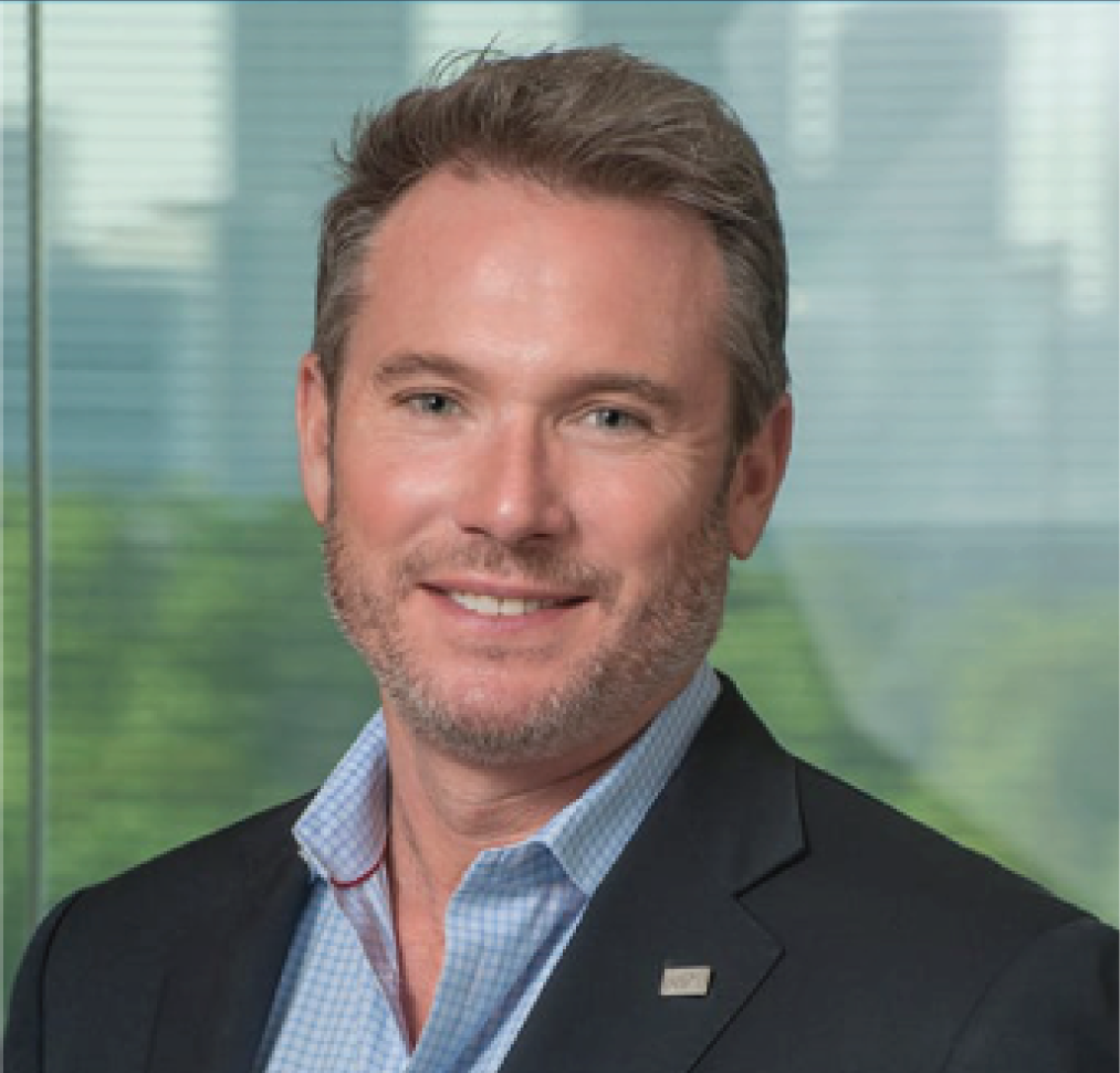 A man in a suit and blue shirt is smiling for the camera.