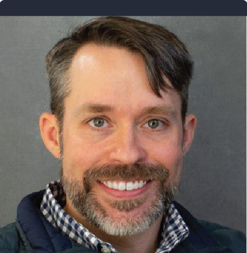 A man with a beard and mustache is smiling for the camera.