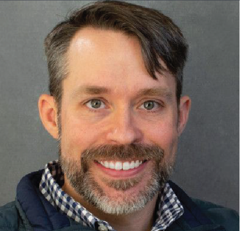 A man with a beard and mustache is smiling for the camera.