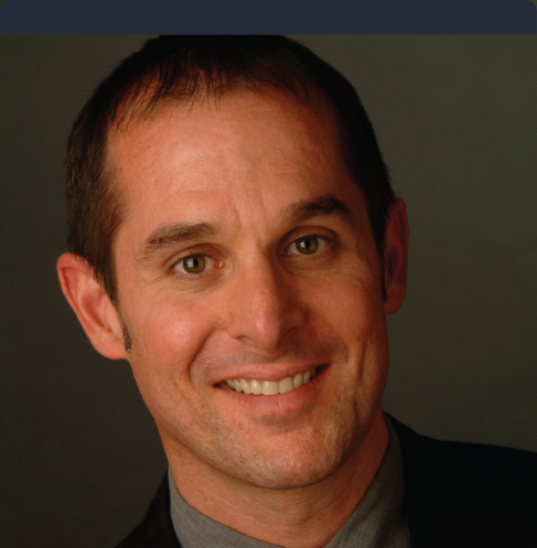 A man in a suit and tie smiles for the camera