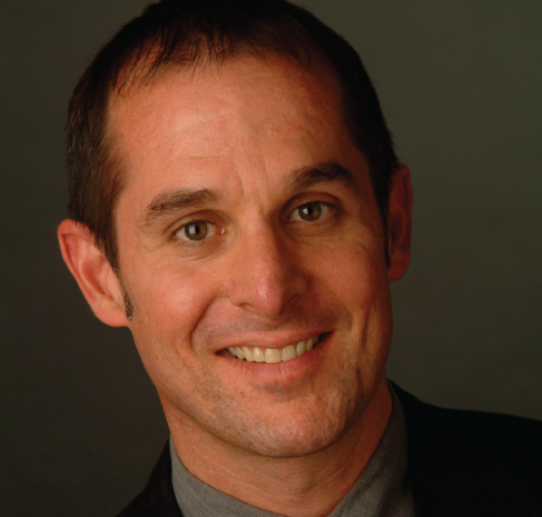 A man in a suit and tie smiles for the camera