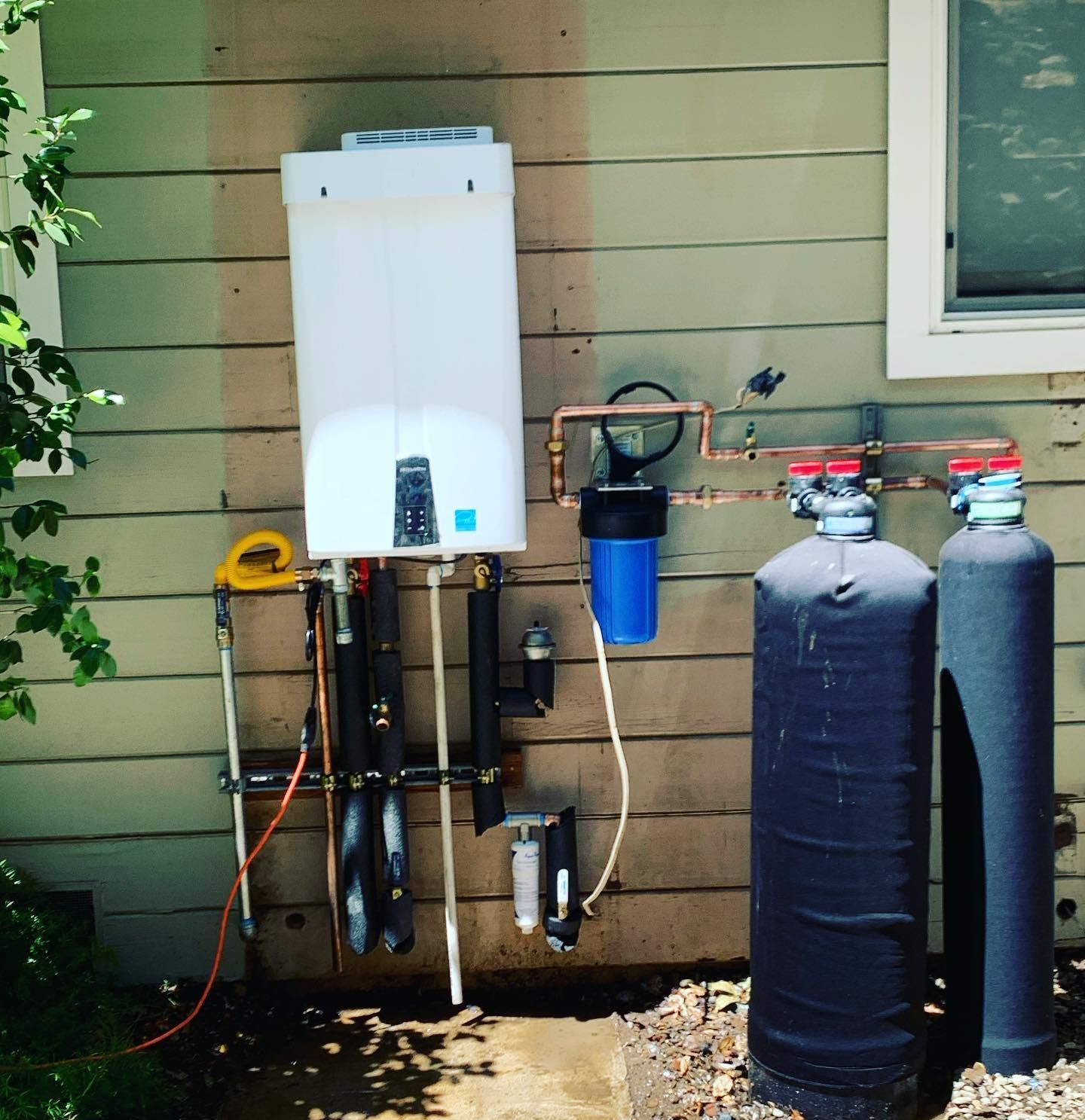 Water heater and filtration system mounted on the exterior wall of a house.