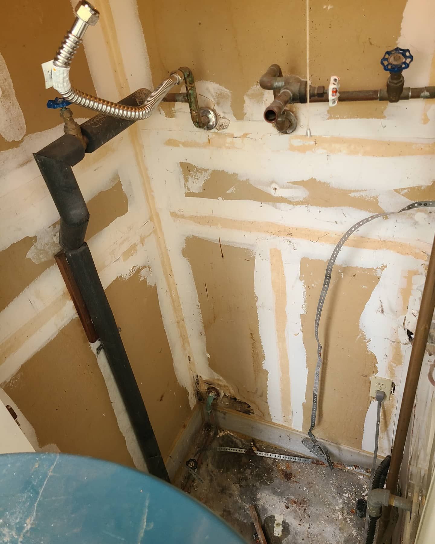 Laundry room with exposed pipes and unfinished drywall. Blue wash basin visible.