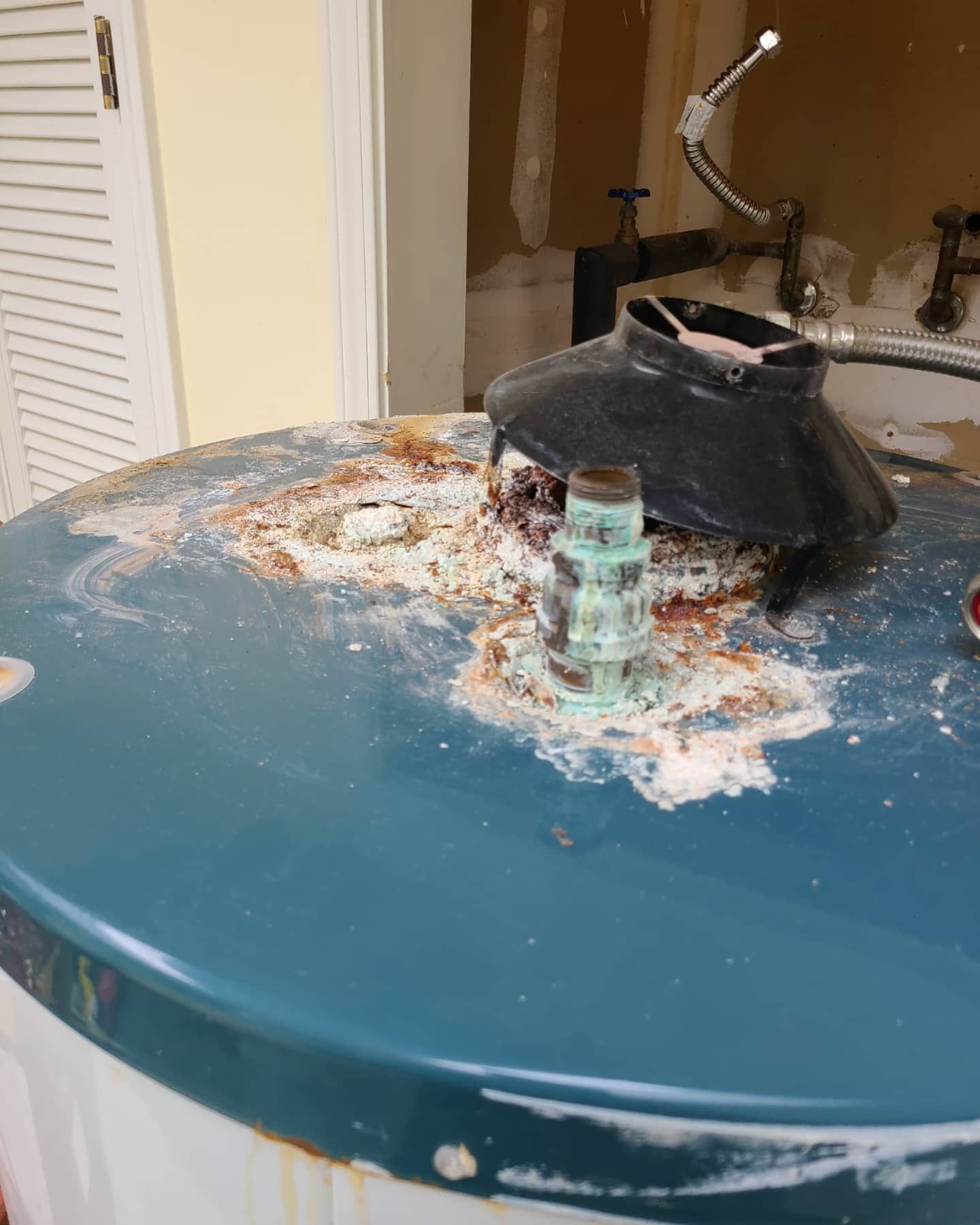 Blue water heater with corrosion and debris, near a sink.