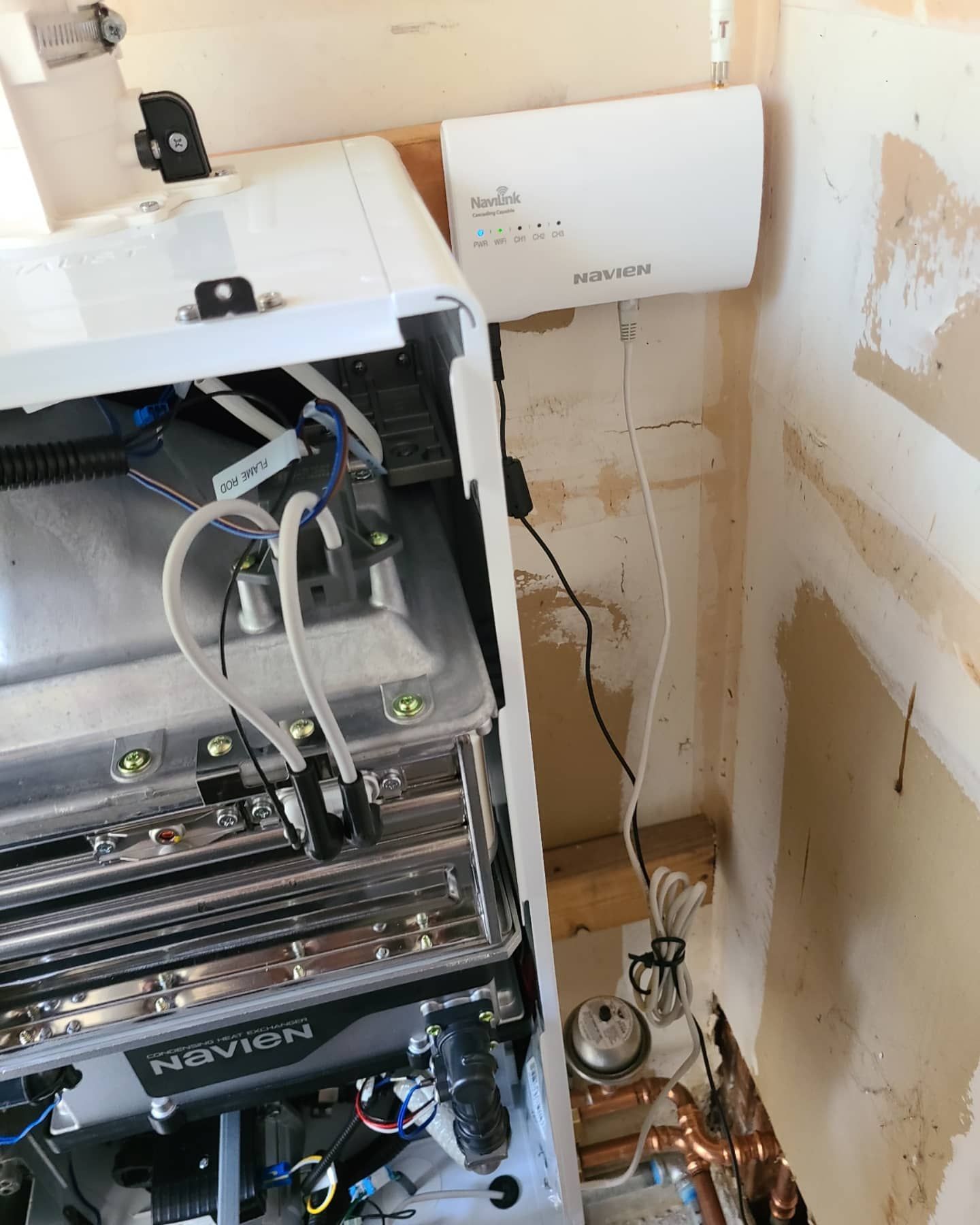 Gas boiler with a white control panel, installed in a partially finished wall.