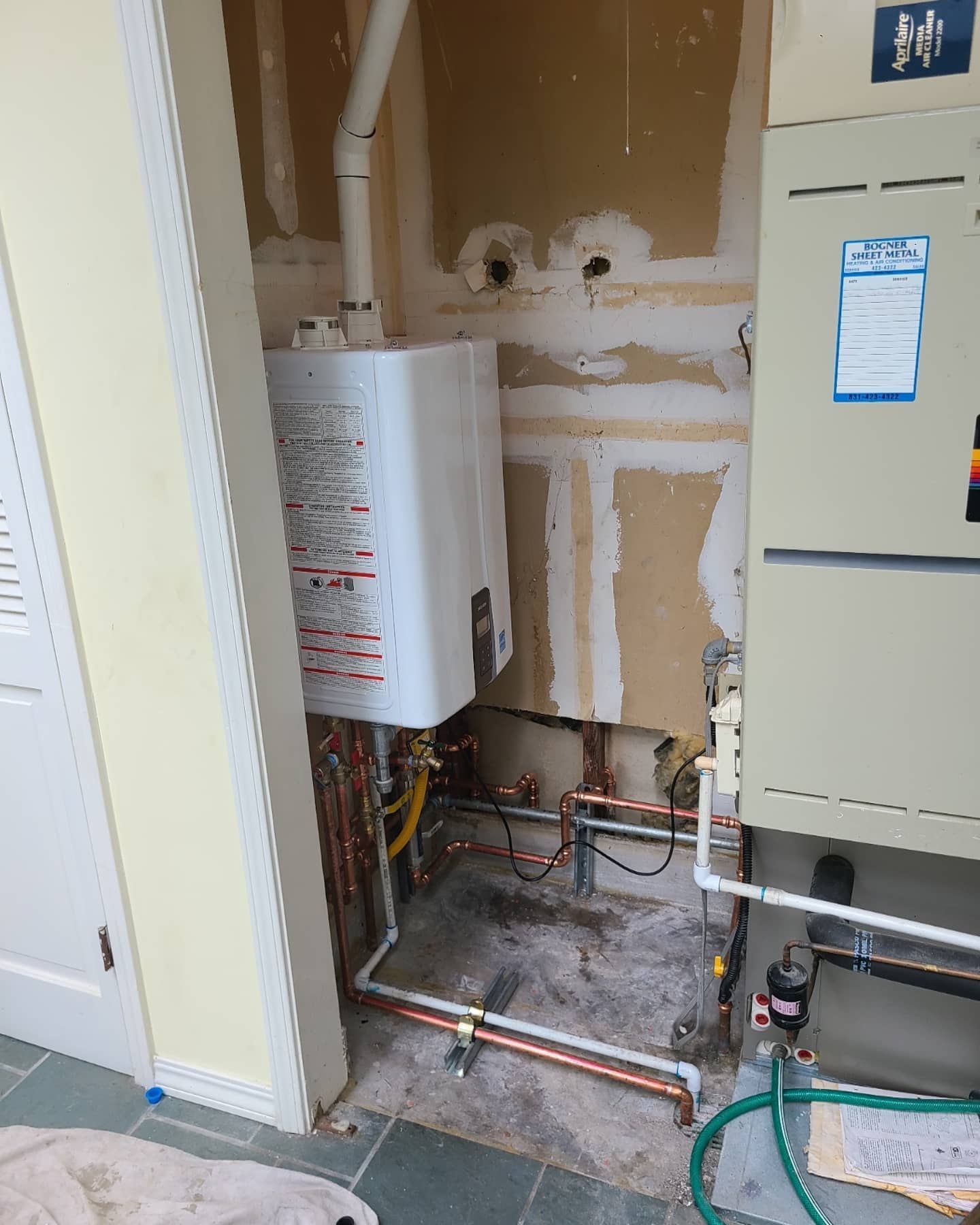Gas water heater and HVAC unit in unfinished room with exposed pipes.