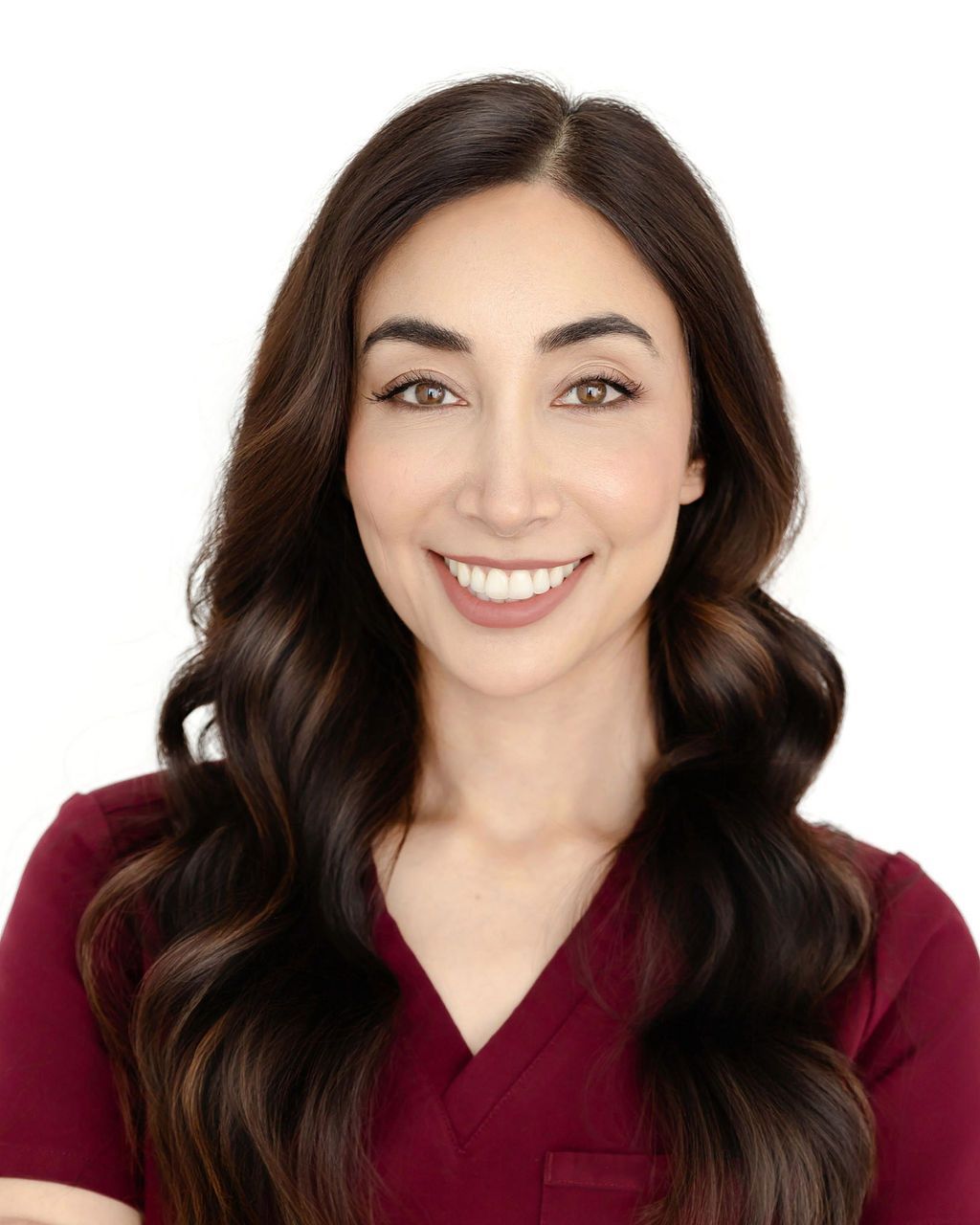 A woman in a white coat is smiling while sitting in a chair