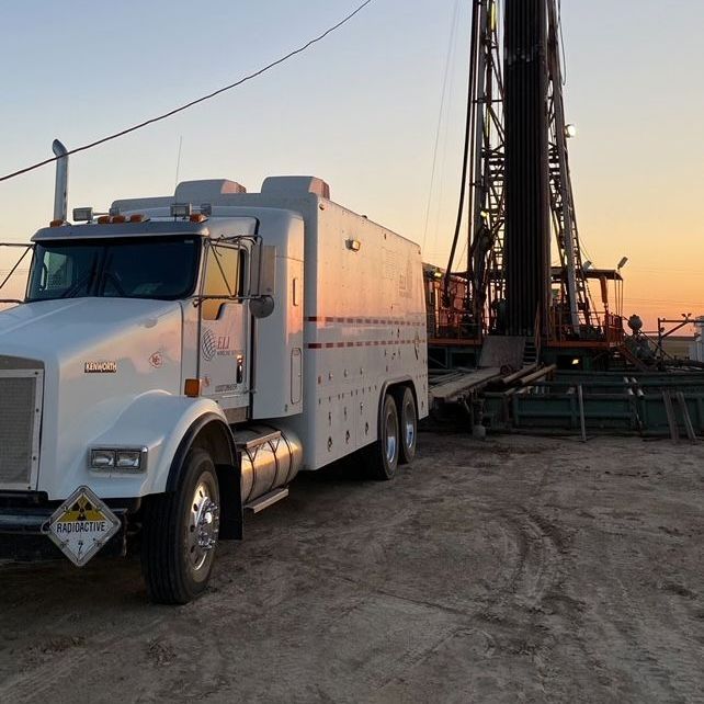 A kenworth truck is parked in front of a drilling rig
