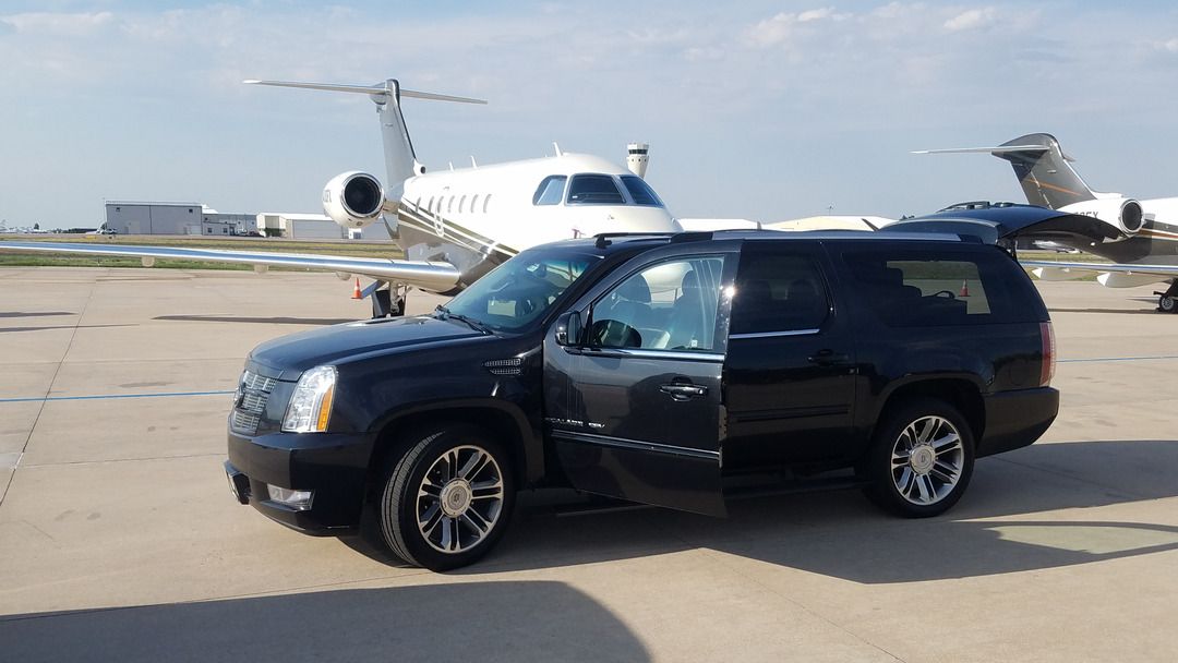 A black suv is parked in front of a private jet