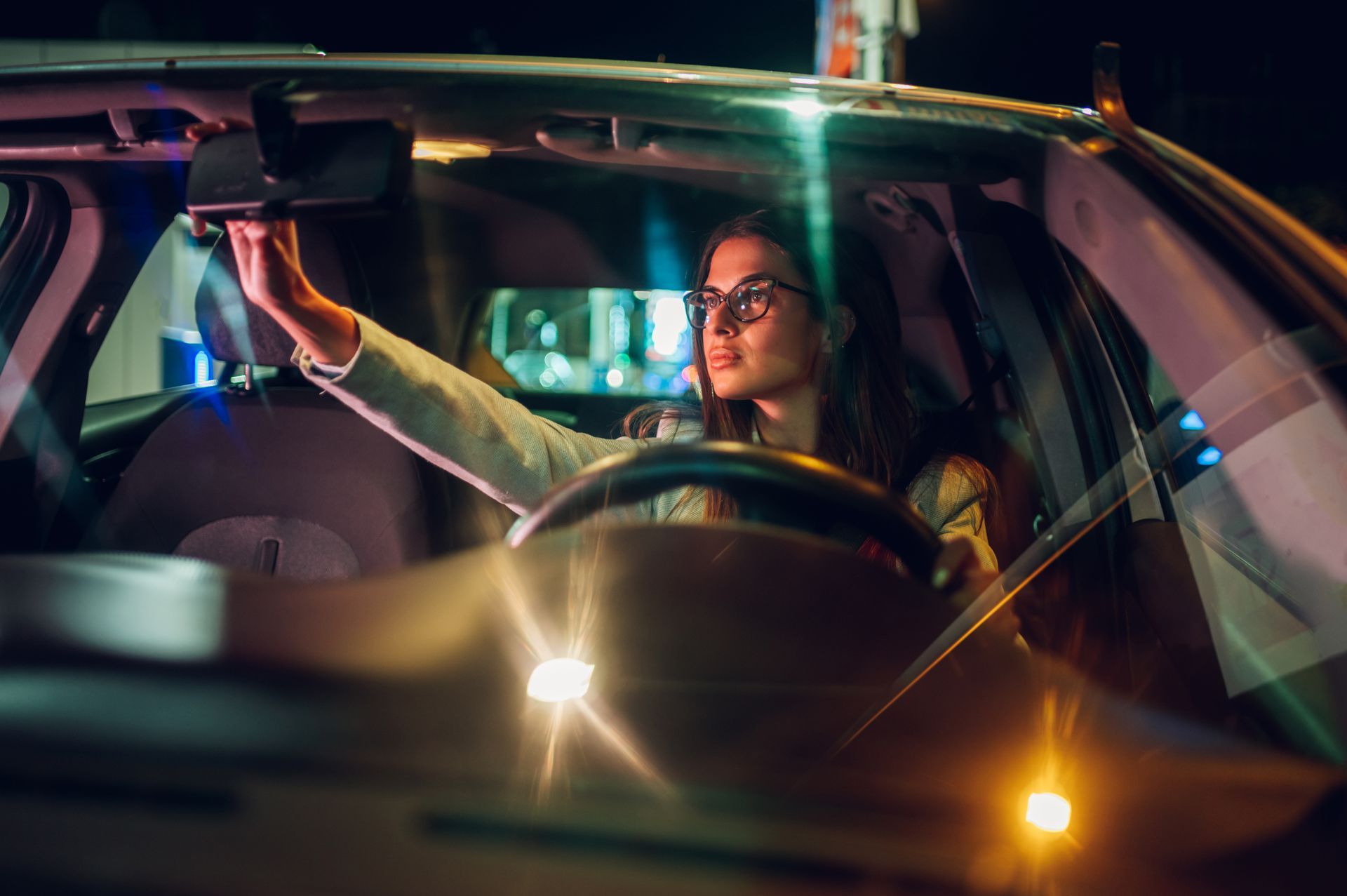 Jeune conductrice qui conduit la nuit avec des lunettes pour plus de confort visuel 