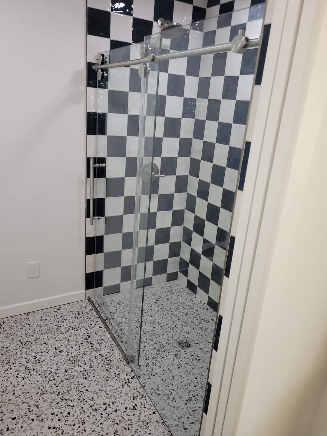 A bathroom with black and white checkered tiles and a sliding glass shower door
