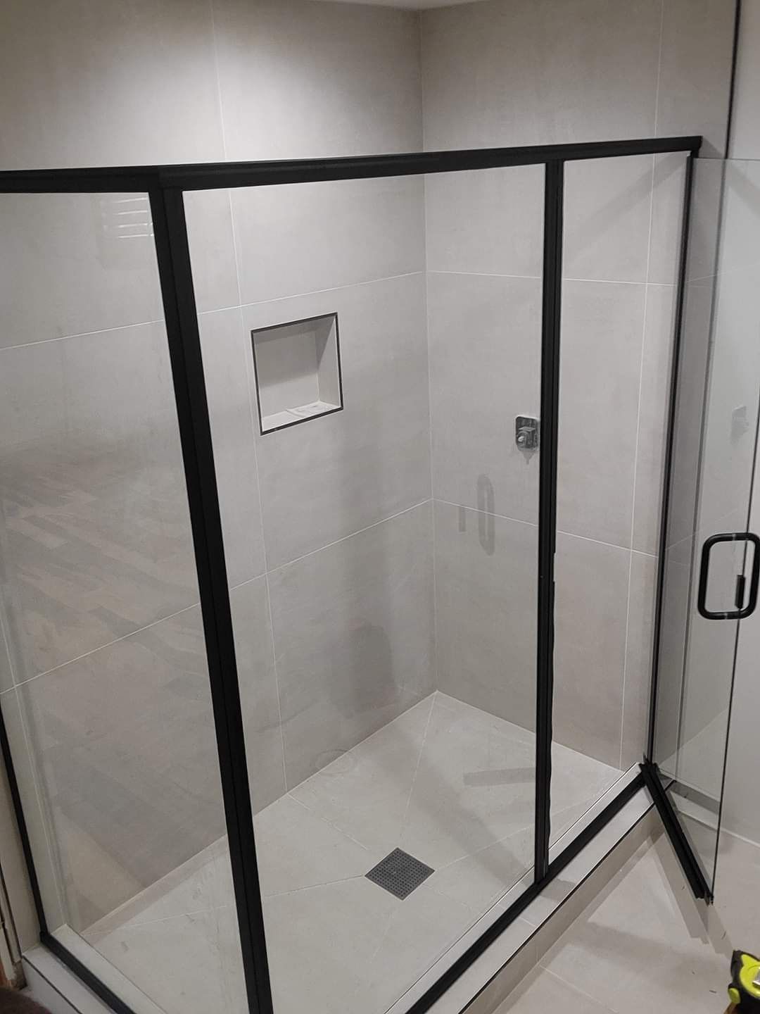 A shower stall with a black frame and clear glass doors in a bathroom.