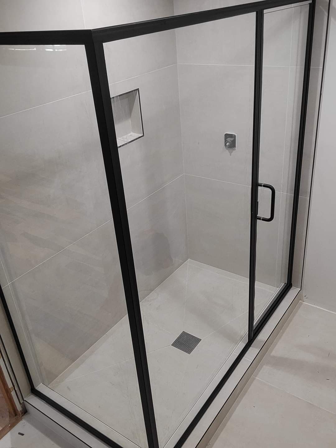 A shower stall with a black frame and glass doors in a bathroom.