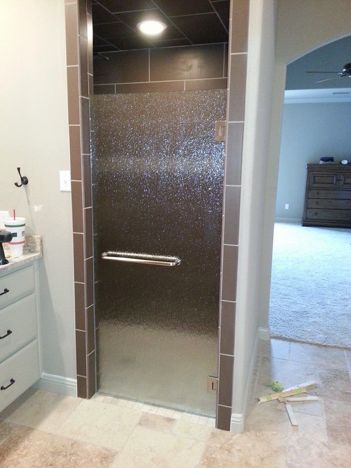 A bathroom with a glass shower door with a handle