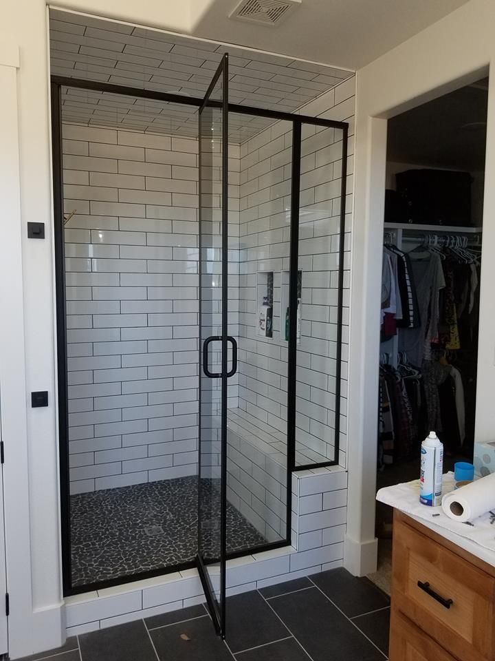 A bathroom with a walk in shower with a black frame.