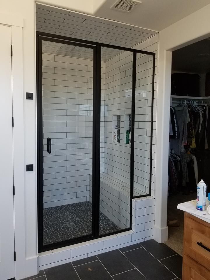 A bathroom with a walk in shower with a black frame