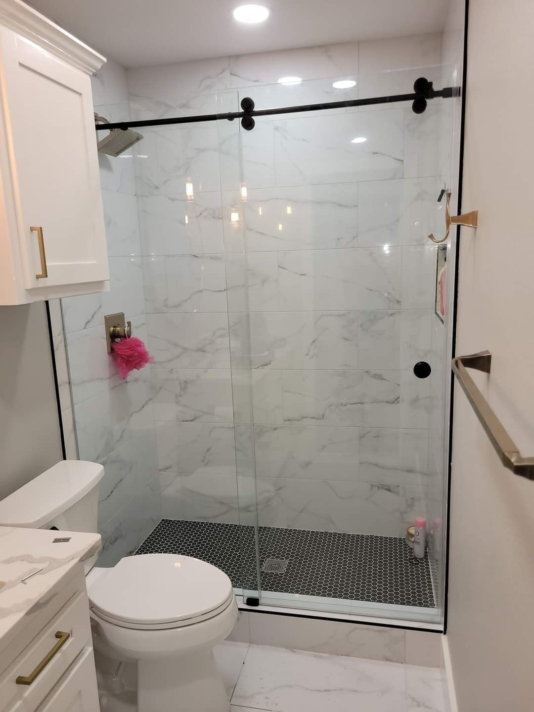 A bathroom with a toilet , sink , shower and sliding glass door.