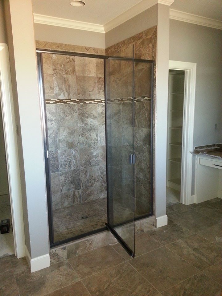 A bathroom with a walk in shower with a glass door.