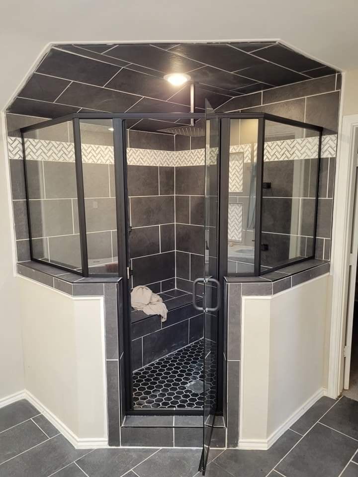 A bathroom with a walk in shower with a glass door.