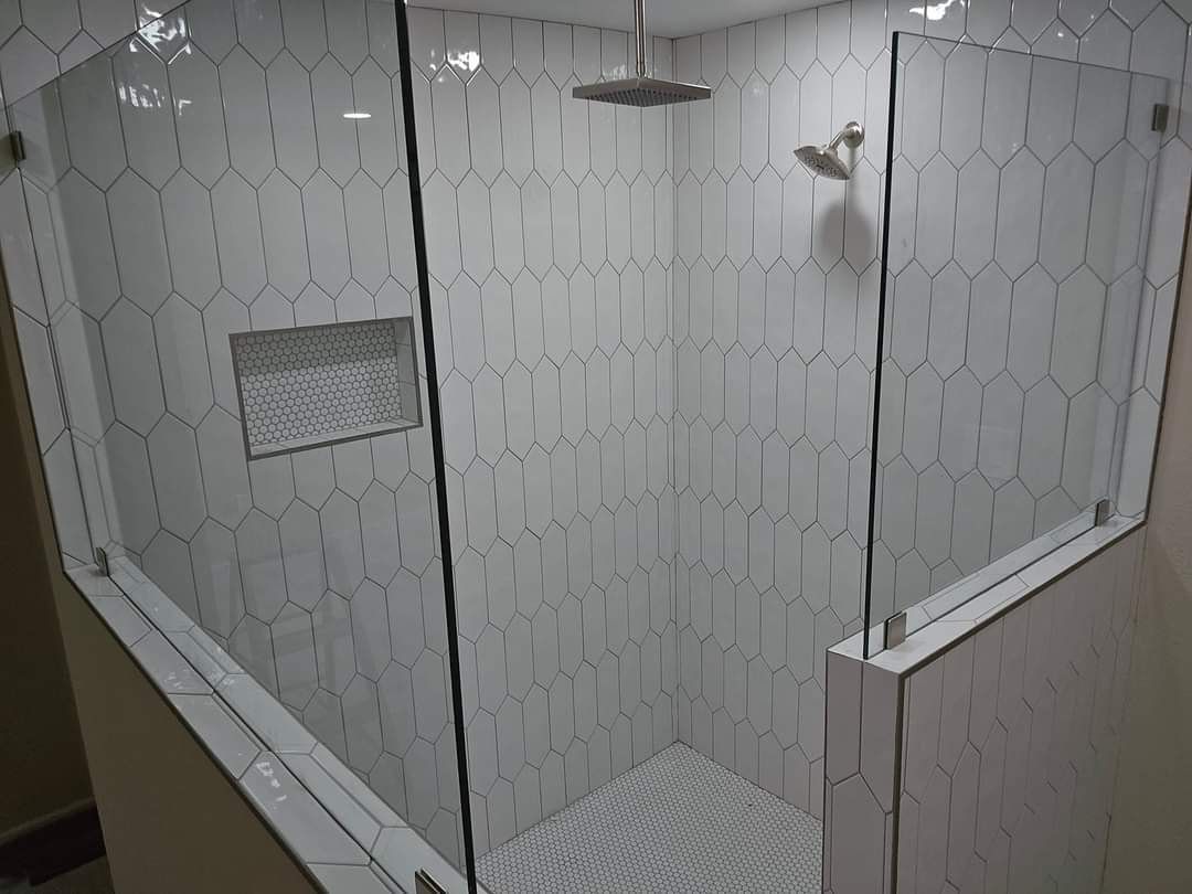 A shower with a glass door and a shower head in a bathroom.