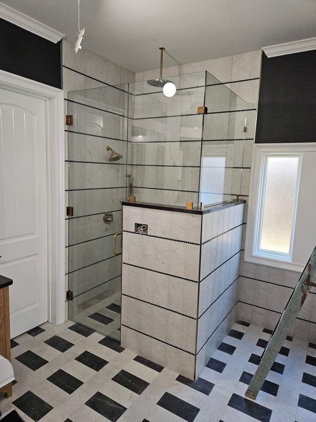 A bathroom with black and white tiles and a walk in shower