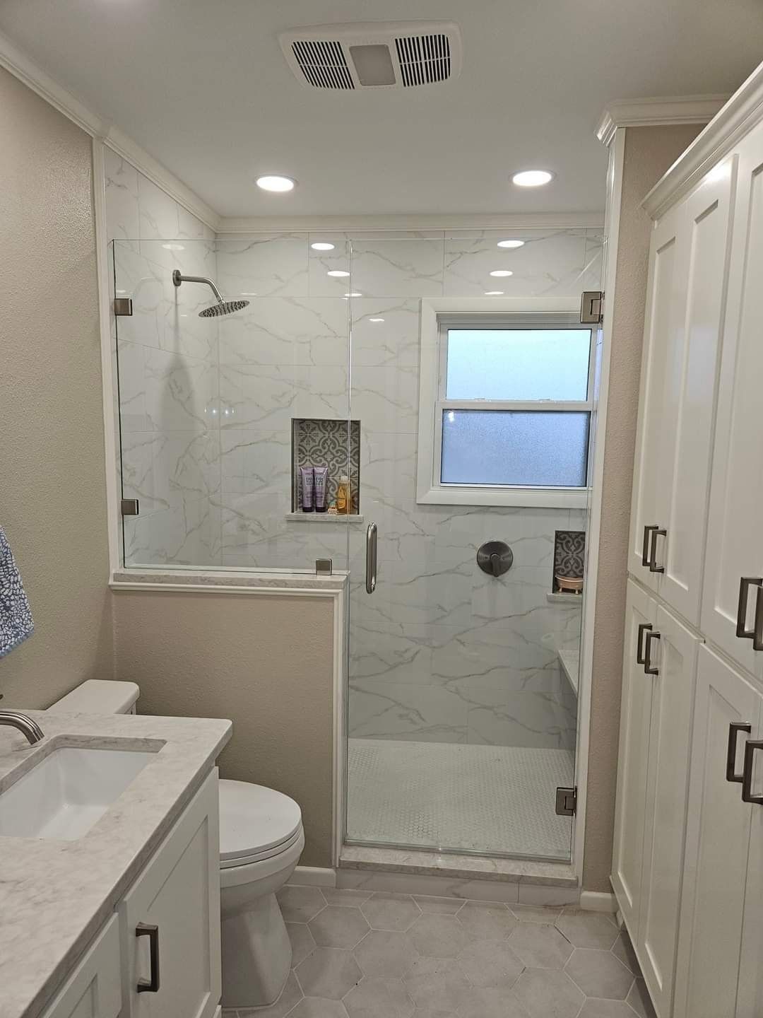 A bathroom with a toilet , sink , shower and window.