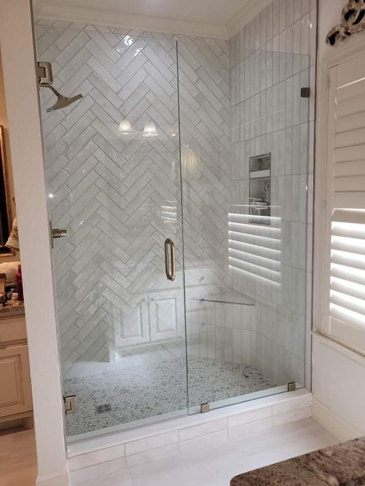 A bathroom with a walk in shower with a glass door.