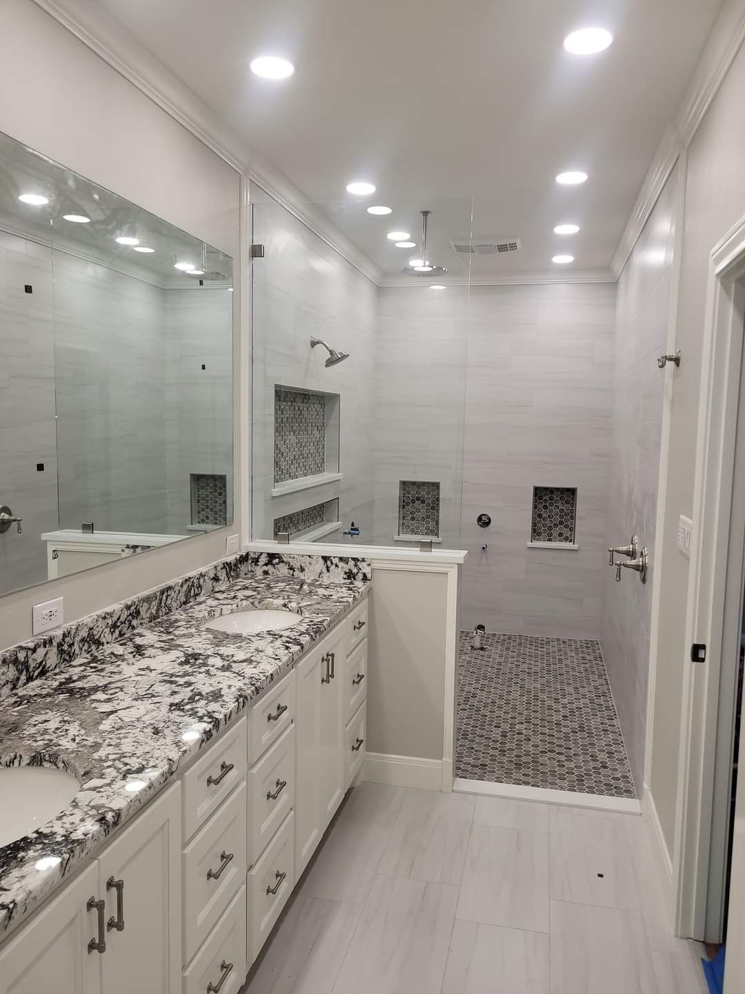 A bathroom with two sinks and a walk in shower.