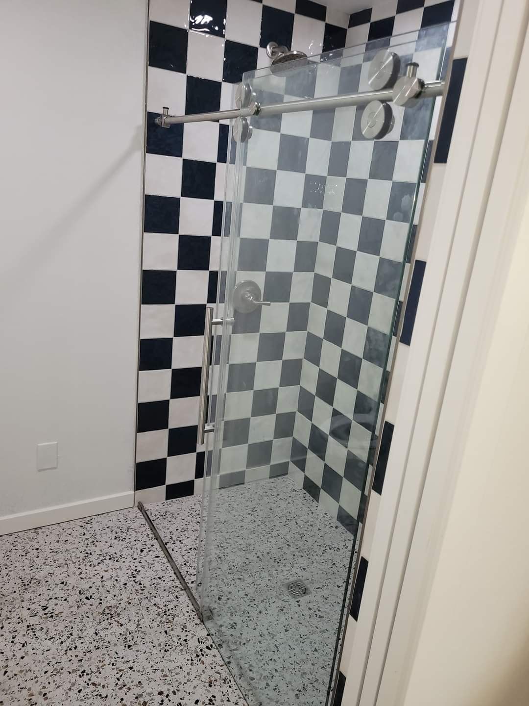 A bathroom with black and white checkered tiles and a walk in shower