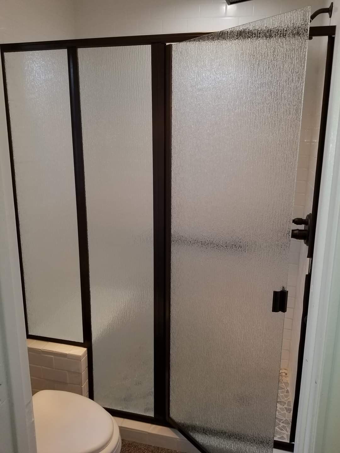 A bathroom with a toilet and a glass shower door.