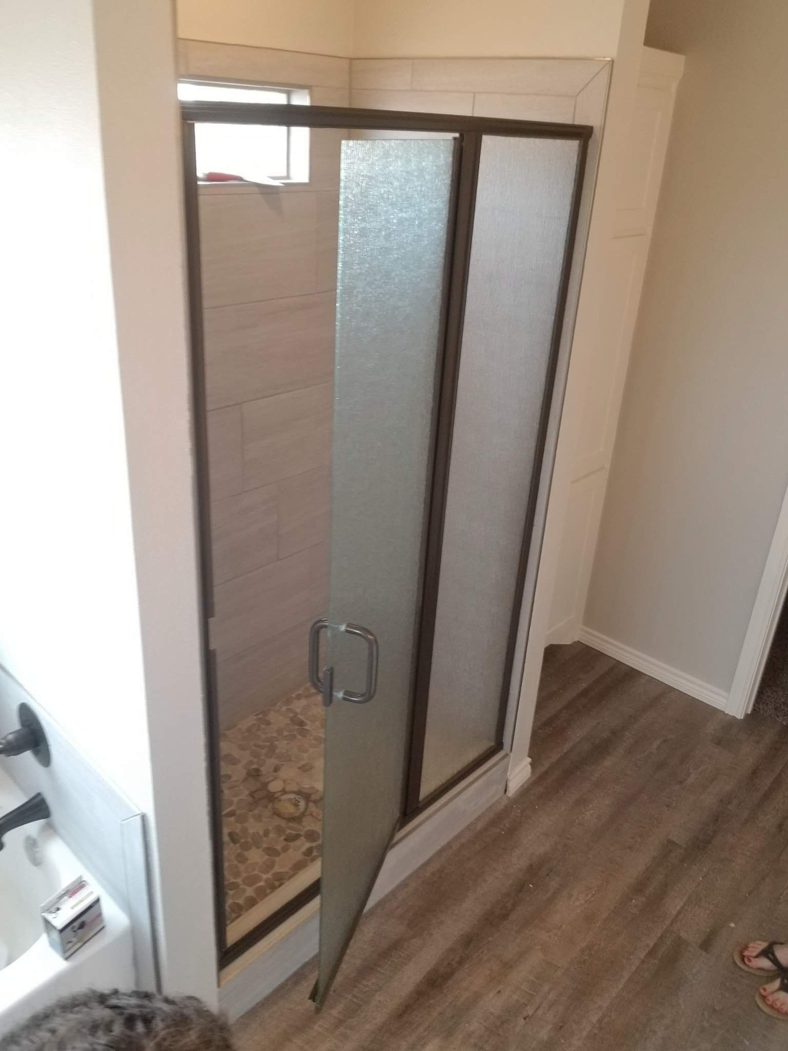 A person is standing in a bathroom next to a shower stall.