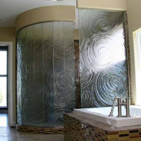 A bathroom with a curved glass shower door and a bathtub.