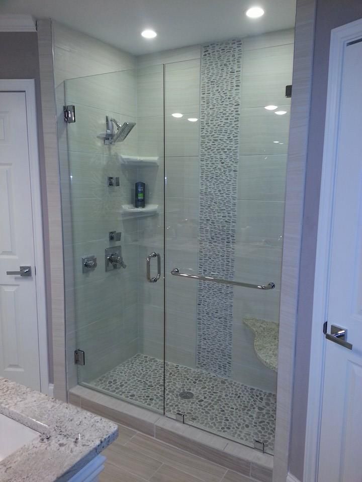A bathroom with a walk in shower with a glass door.