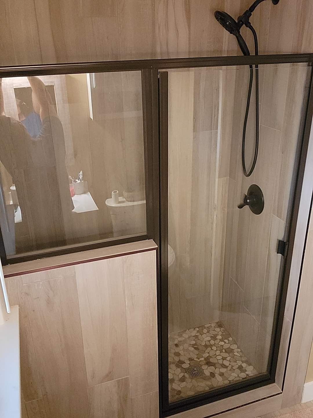 A bathroom with a walk in shower with a glass door and a shower head.