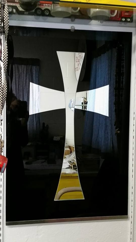 A cross is reflected in a mirror in a room.