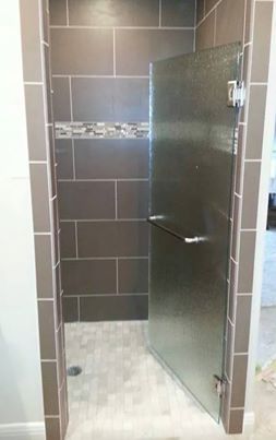 A bathroom with a walk in shower with a glass door.