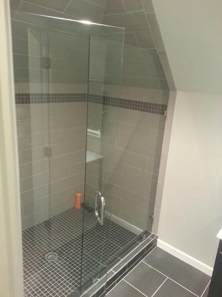 A bathroom with a walk in shower with a glass door.
