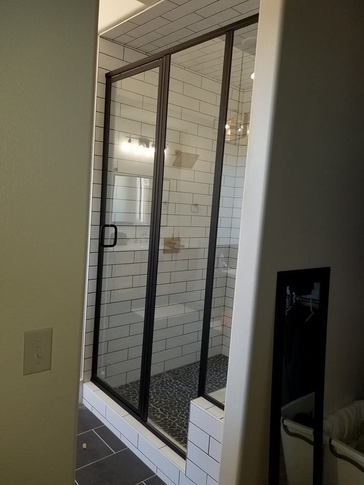 A bathroom with white brick walls and a walk in shower.
