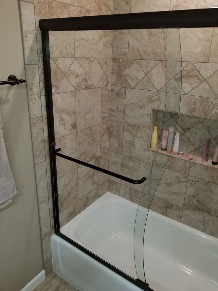 A bathroom with a bathtub and a glass shower door.
