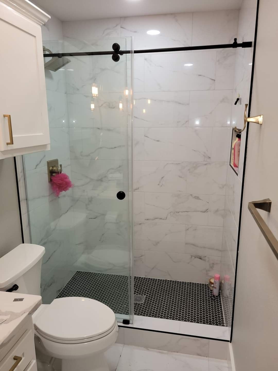 A bathroom with a toilet , sink and shower with a glass door.