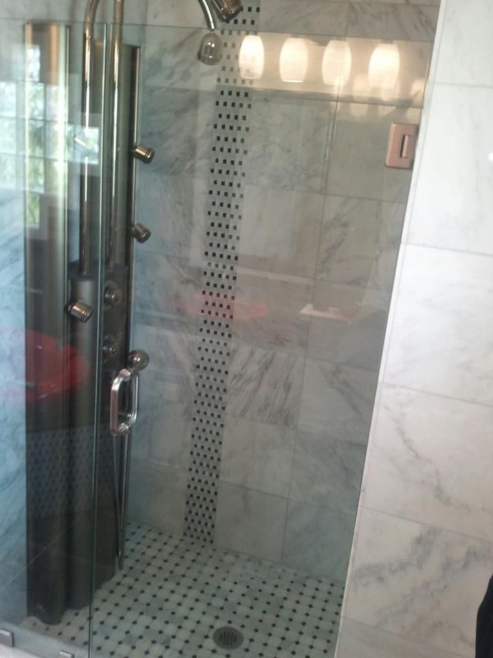 A walk in shower with a black and white tile floor