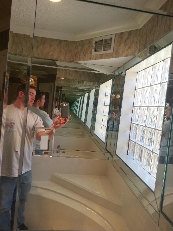 Two men are taking a picture of themselves in a bathroom mirror.