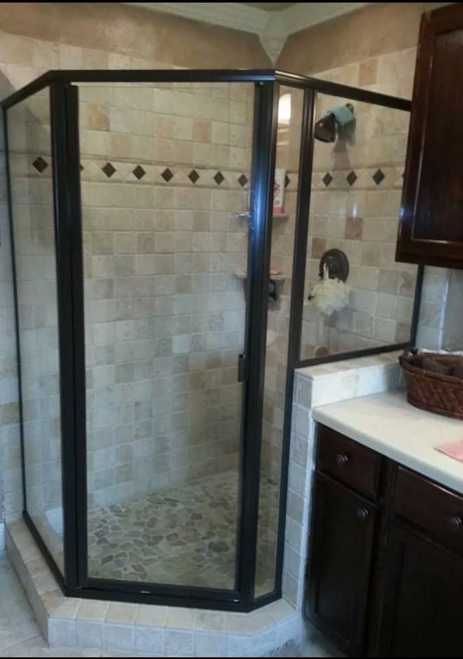 A bathroom with a walk in shower with a black frame