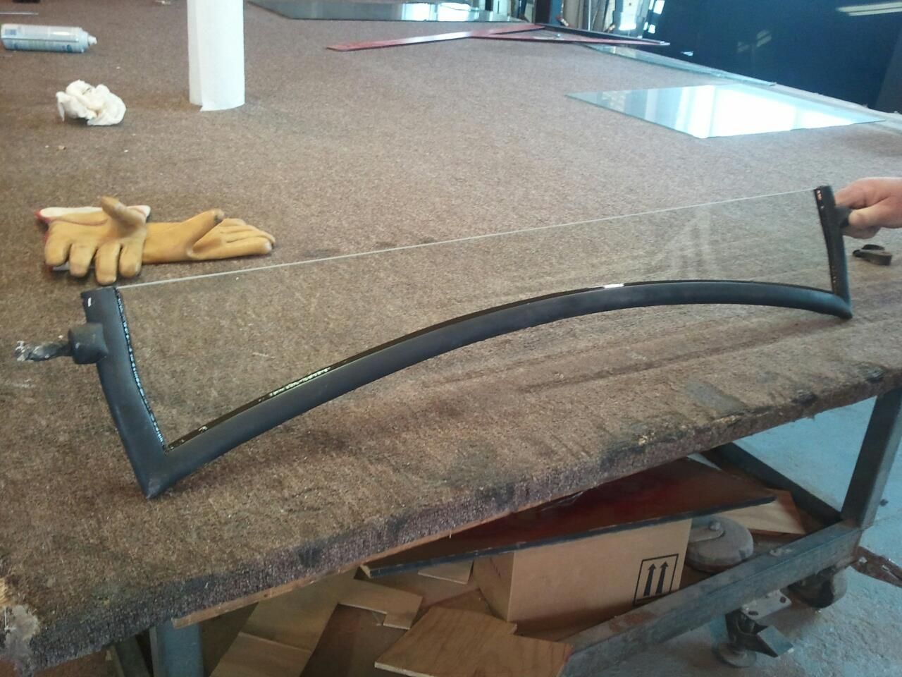 A person is cutting a piece of glass with a saw on a table