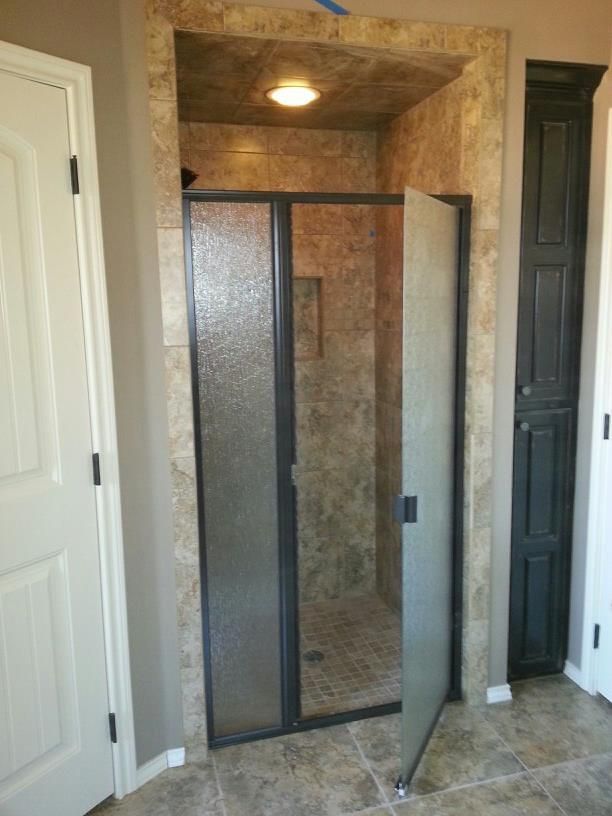 A bathroom with a walk in shower with a glass door